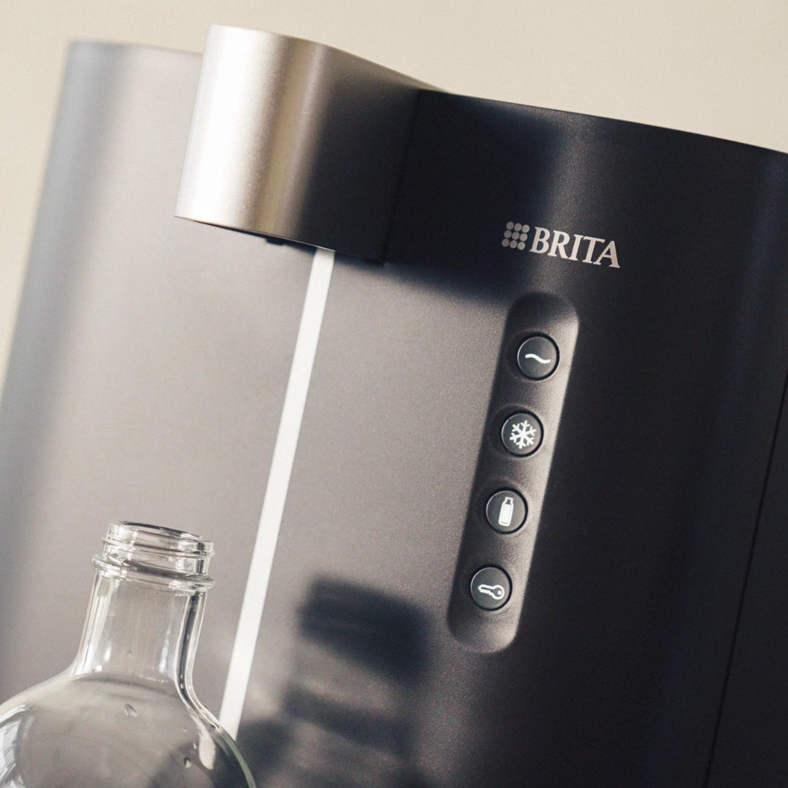 BRITA Top Compact con una bottiglia trasparente sotto, su uno sfondo neutro.