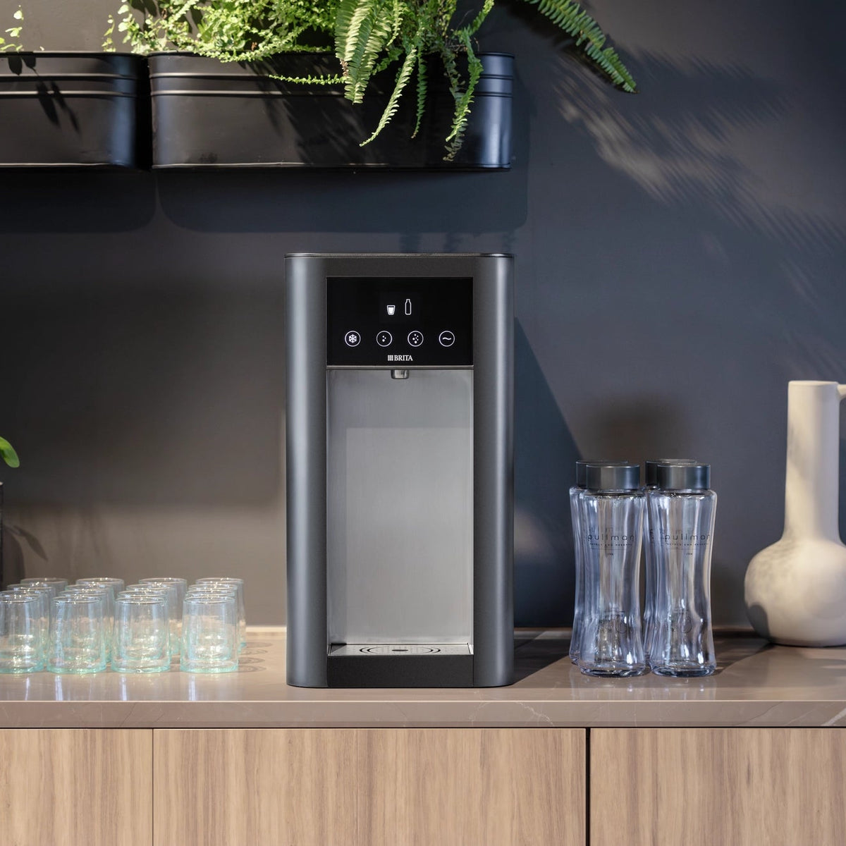 Top Pro un distributore d'acqua sul piano di lavoro della cucina, con bicchieri e bottiglie, in un ambiente da cucina moderno.